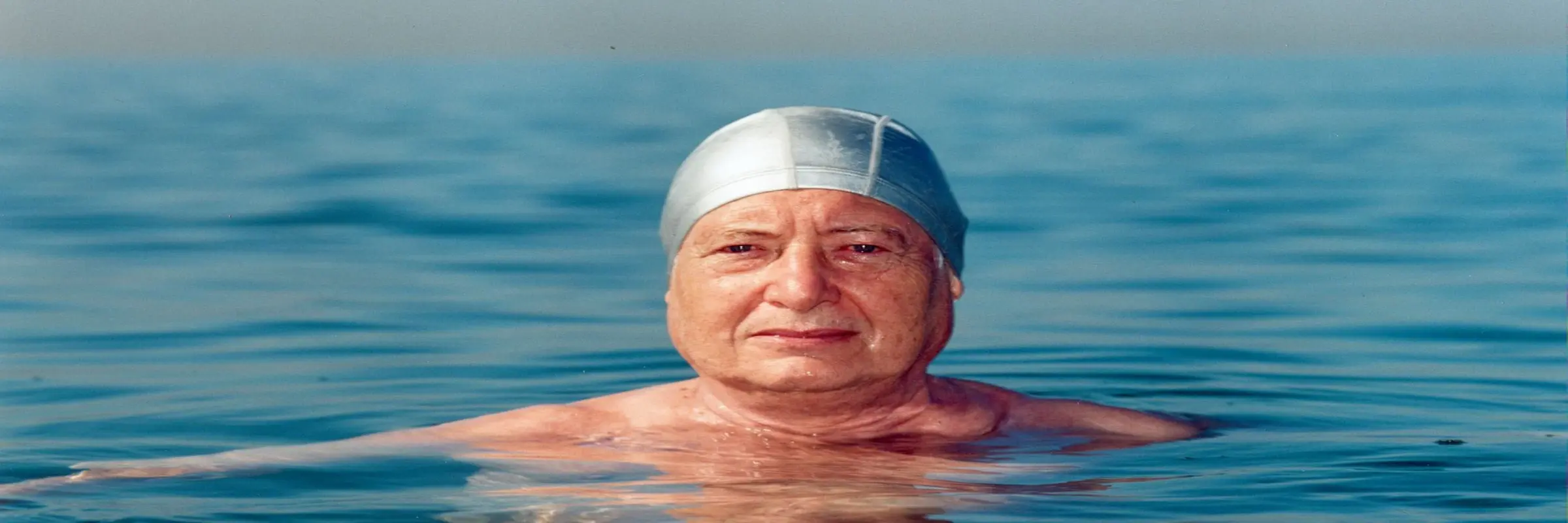 ein Mann schwimmend im Wasser mit Badekappe