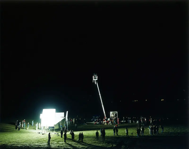 Menschen auf einer Wiese bei Nacht, schauen auf hell leuchtende Leinwand