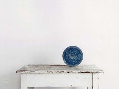 eine blaue Kugel liegt auf einem weißen Tisch vor weißem klaren Hintergrund