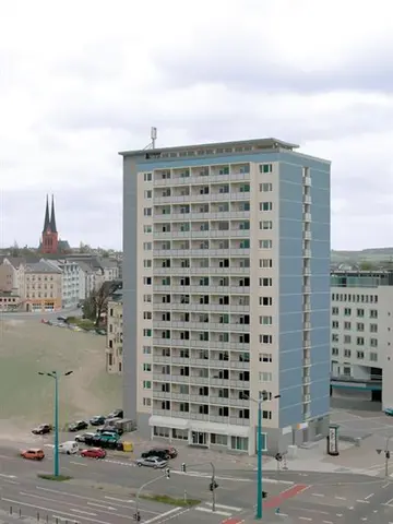 Ein Plattenbau, davor eine befahrene Straße